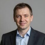 Профессиональный портрет уверенного российского бизнесмена с дружелюбным взглядом на размытом нейтральном фоне
